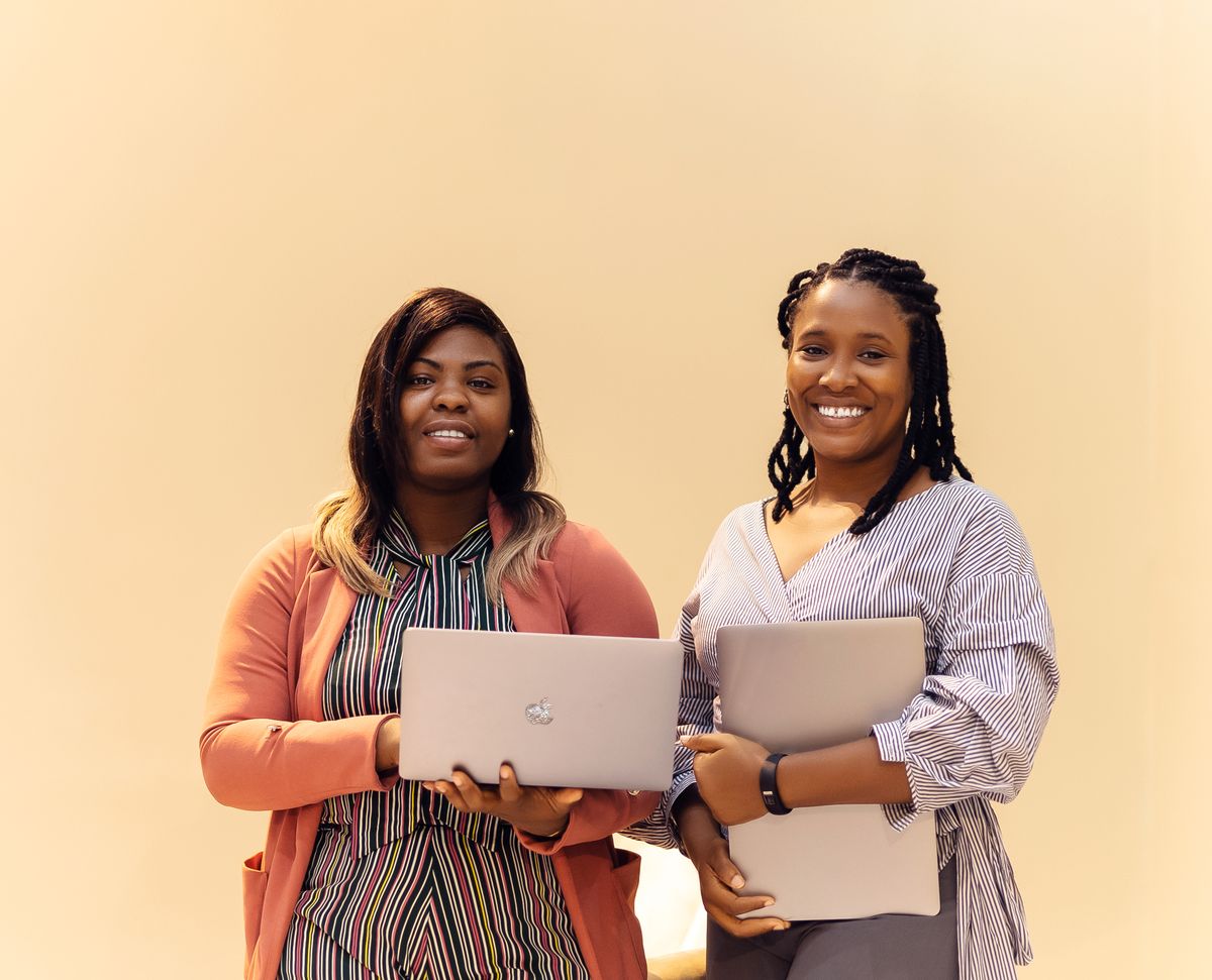 Two businesswomen holding laptops in a Lagos office